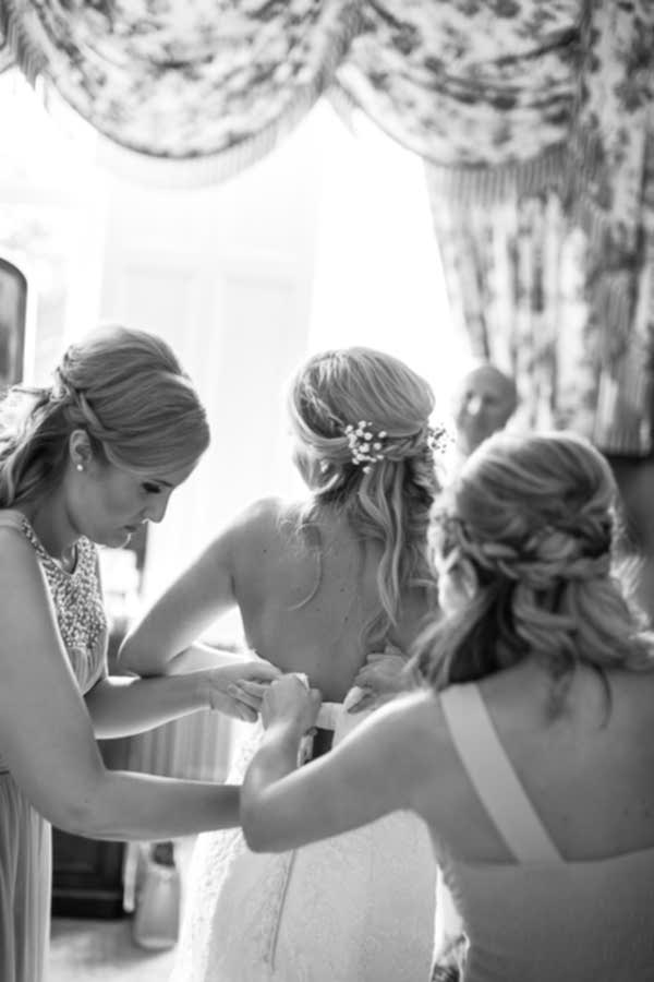 bridesmates helping bride to get into wedding dress