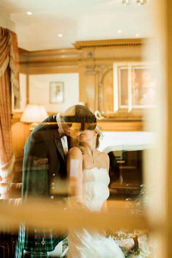 view through window bride and groom kissing