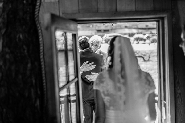 dad embracing groom after wedding