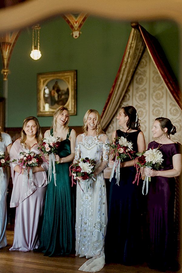 reflection in teh mirror of bridesmates laughing holding flowers