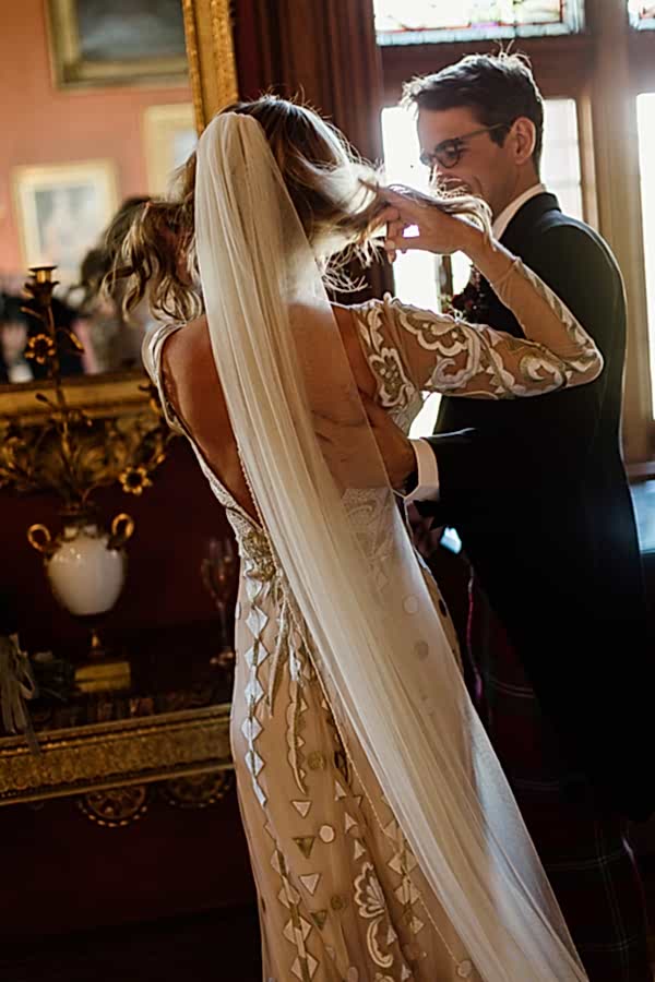 bride fixing her hair groom holding her