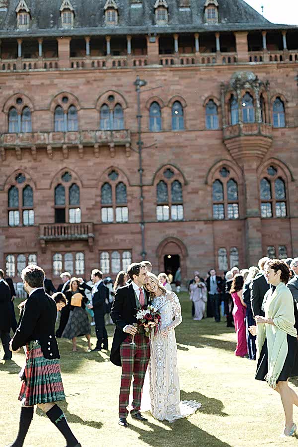 newlt married couple huging each other with guests around them